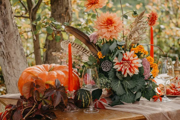 Autumn romantic setting: Bouquet of dahlias, pomegranates, candles, pumpkins and glasses — Stock Photo, Image