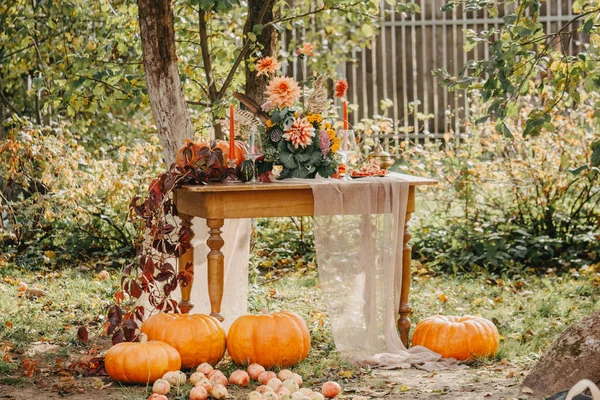 Herbst-Romantik: Bouquet aus Dahlien, Granatäpfeln, Kerzen, Kürbissen und Gläsern — Stockfoto