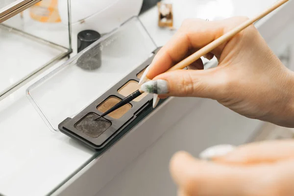 O artista de maquiagem menina digita um produto cosmético na escova. close-up — Fotografia de Stock
