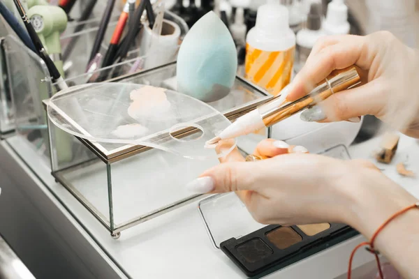 O artista de maquiagem menina digita um produto cosmético na escova. close-up — Fotografia de Stock