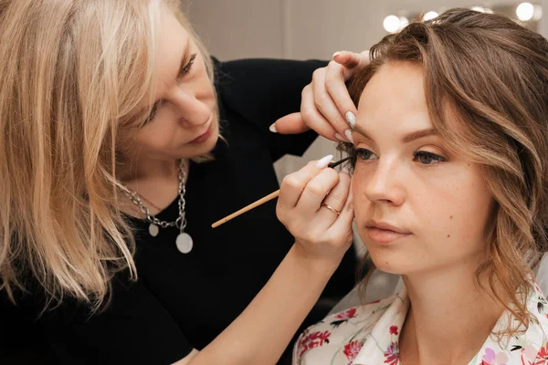 A filmar num salão de beleza. artista de maquiagem aplica maquiagem para uma jovem noiva linda menina. — Fotografia de Stock