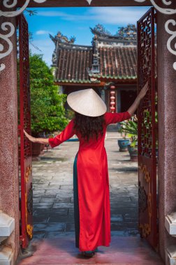 Geleneksel Vietnam şapkalı ve geleneksel elbiseli bir kadın turist Budist tapınağını ziyaret ediyor..