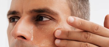 Gözün altındaki deriye kozmetik göz bandı yapıştıran bir adam. panoramik