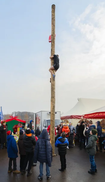 Jovem sobe um poste para um presente durante a diversão Shrovetide — Fotografia de Stock