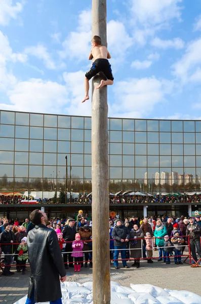 Menino sobe no pilar atrás do presente durante entretenimentos Shrovetide — Fotografia de Stock