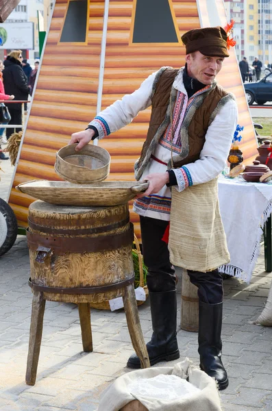 Man is showing work of old hand-mill during Shrovetide entertainment outdoor — Stock Photo, Image