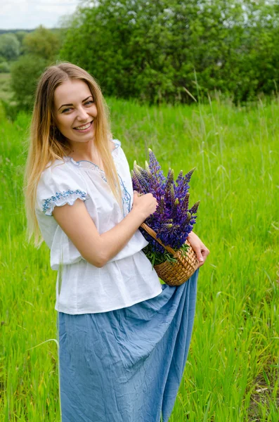 Vacker flicka med korg med vilda blommor i händer — Stockfoto