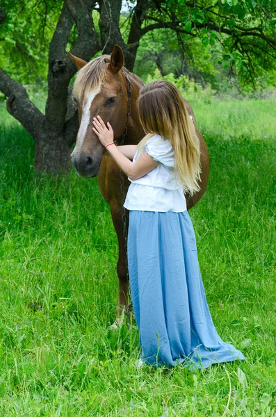 Девушка обнимает лошадь в яблоневом саду — стоковое фото