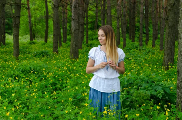 Porträt eines schönen Mädchens im Wald inmitten von Blumen — Stockfoto