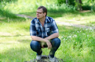 Adam gülümseyen orman çim üzerinde oturur  