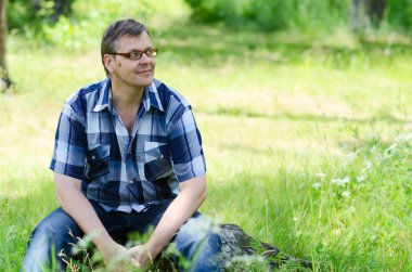 Gülümseyen adam taş orman kenarında oturur güneşli yaz gün