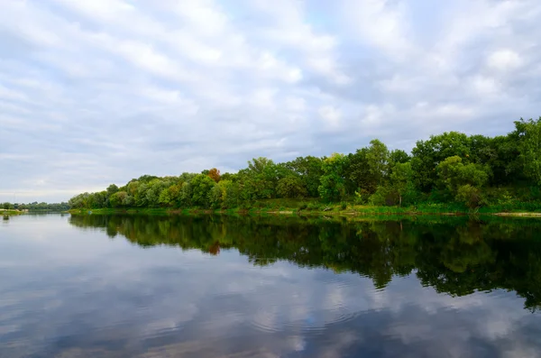 Trees on bank of pond and clouds are reflecting in water — Stock Photo, Image