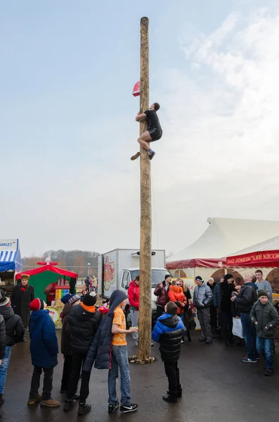 Jovem sobe um poste para um presente durante a diversão Shrovetide — Fotografia de Stock