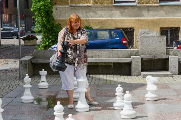 Young cheerful woman holds big chess piece on street in old town of Klaipeda, Lithuania — Stock Photo, Image