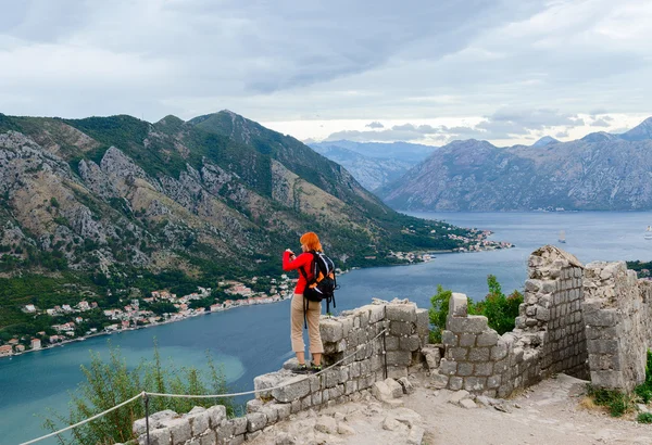 Girl tourist photographs the Bay of Kotor from the fortress wall — Stock Photo, Image