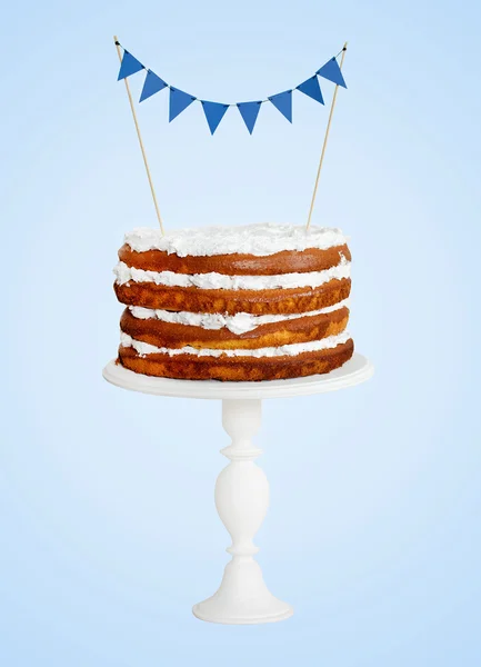 Layer cake with blue flags on white stand — Stock Photo, Image