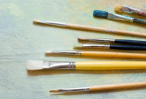 Paint brushes on an oil canvas — Stock Photo, Image