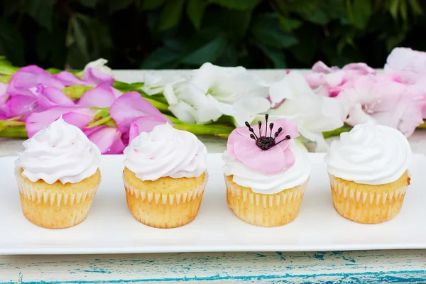 Çiçekli beyaz plaka üzerinde dört dekore edilmiş cupcakes
