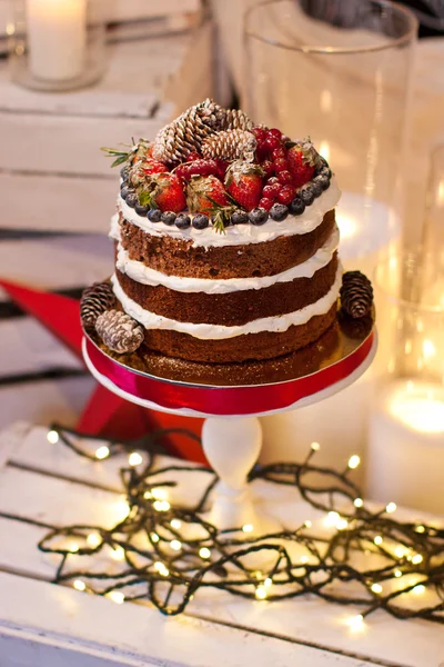 Pastel de capa decorado con bayas en soporte blanco y guirnalda — Foto de Stock