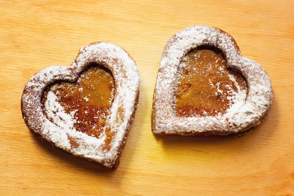 Ahşap arka planda iki kalp şeklinde kurabiye.