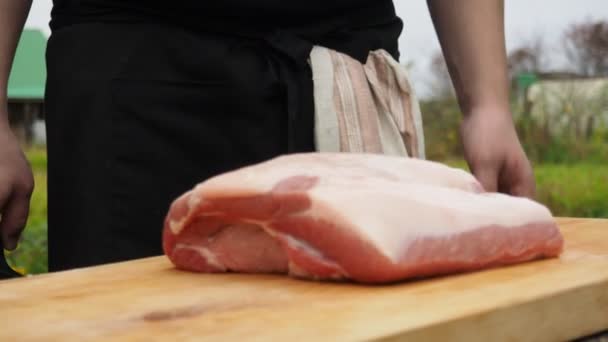 Ein Mann wirft ein Stück Schweinefleisch auf ein Schneidebrett. Fleisch in Stücke schneiden — Stockvideo