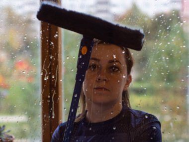 Bir kadın evde pencereleri yıkıyor. Teleskopik saplı pencere temizleme paspası.