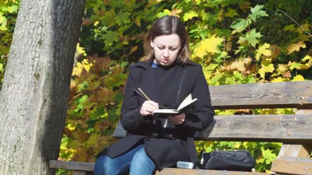 若い女性がベンチに座りながら鉛筆で自然を描きます — ストック動画