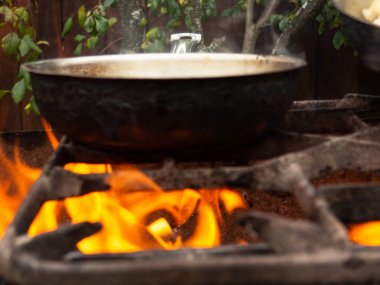 Parlak bir ateşte kızartma tavası. Temiz havada yemek pişirmek. Yanan ızgara