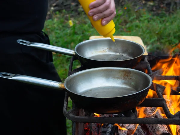 平底锅放在烤架上 烤架放在明亮的炉火上 一个人在平底锅里的火上做饭 — 图库照片