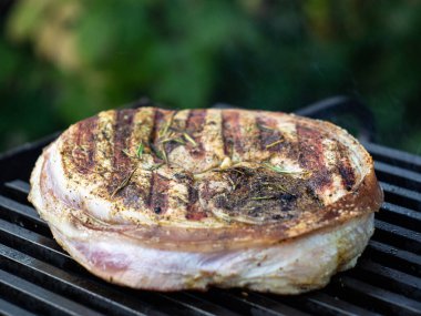 Kemiğin üzerinde büyük bir parça domuz budu ızgarada kızarır. Izgarada yemek pişirmek.