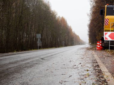 Sağdaki servis yolu tabelası. Yolun kenarında özel ekipman var. Yolda geçici trafik işaretleri var. Yolların onarımı.