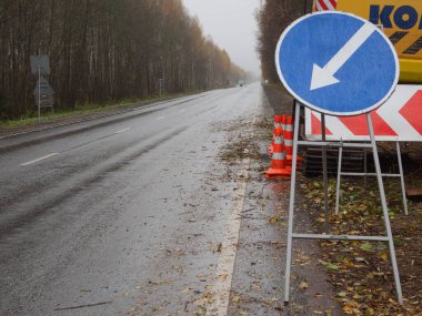 Sağdaki servis yolu tabelası. Yolda geçici trafik işaretleri var. Yolların onarımı