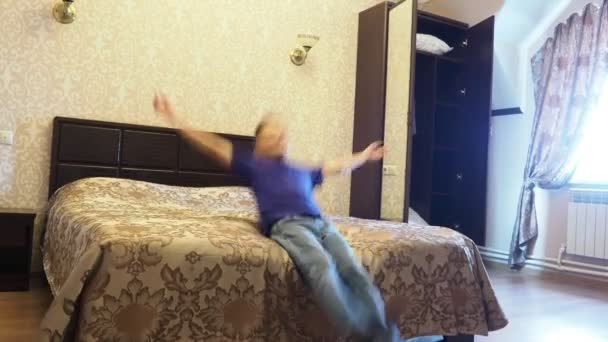 Мальчик падает на кровать в гостиничном номере — стоковое видео
