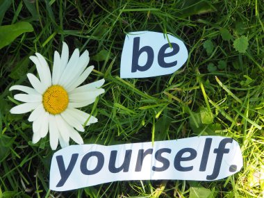 Kendin ol. Kağıt kesikli kelimelerden oluşan çimlerin üzerinde.