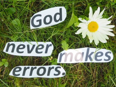 Tanrı asla hata yapmaz. Kağıt kesikli kelimelerden oluşan çimlerin üzerinde.