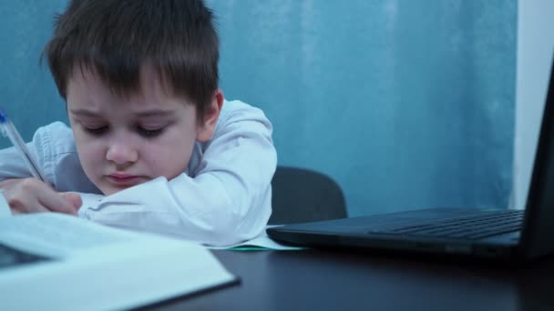 En pojke i skjorta skriver med en penna i en anteckningsbok. Strykningar — Stockvideo