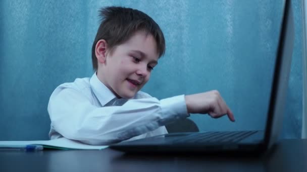 Un ragazzo in un tipo di camicia sulle chiavi di un computer portatile, poi ride — Video Stock