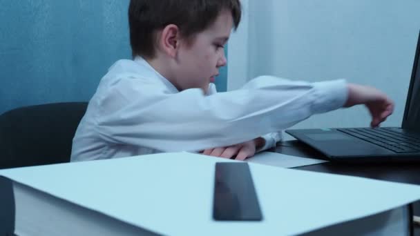 Un chico con una camisa escribe un dedo en las llaves del portátil — Vídeos de Stock