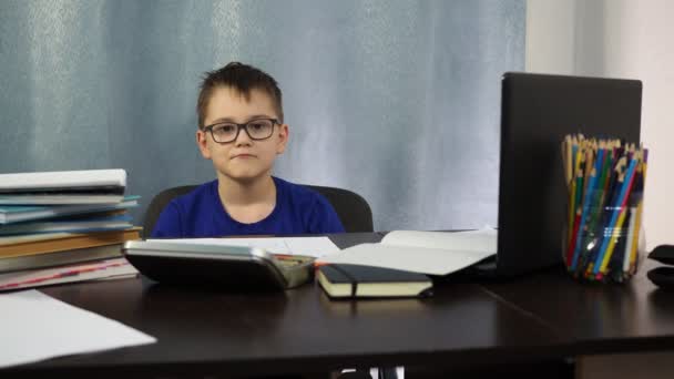 Ένα αγόρι με γυαλιά που κάθεται στο τραπέζι δείχνει τη γροθιά του. Είναι τόσο θυμωμένος για την απομακρυσμένη μελέτη. Σταματήστε τον κορωνοϊό — Αρχείο Βίντεο