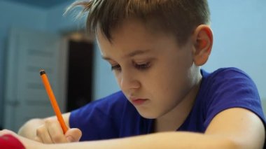 Çocuk yazar, sonra başını kameraya çevirir ve düşünür.