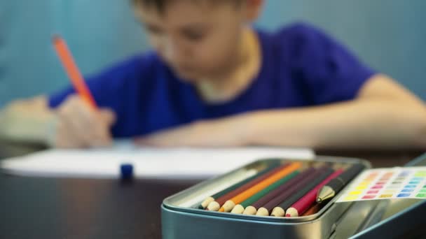 Pojken ritar med pennor. pojke i ur fokus, pennor i förgrunden — Stockvideo