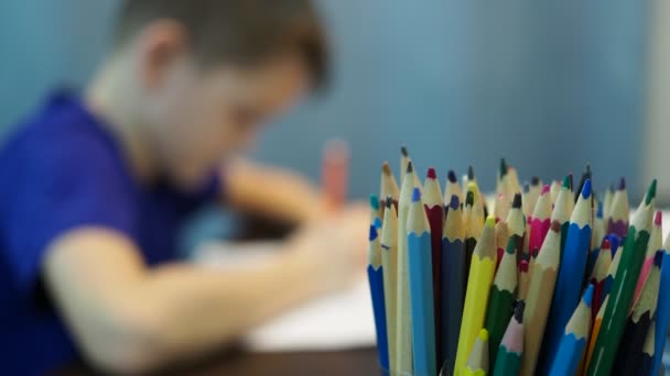 一个男孩在纸上画画。男孩注意力不集中，铅笔在前景中 — 图库视频影像