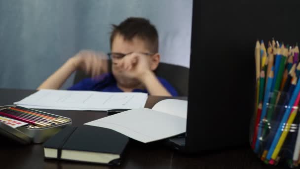 Το αγόρι κοιμάται καθισμένο στο τραπέζι. κουραστική απομακρυσμένη μελέτη — Αρχείο Βίντεο