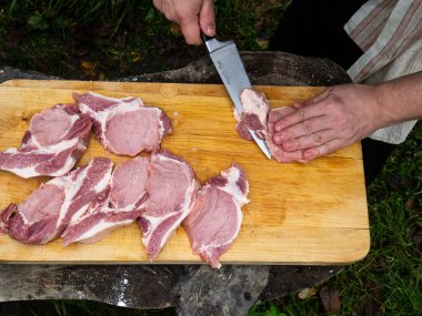 Bir adam etten biftek keser. Domuz filetosu. Yukarıdan görünüm.