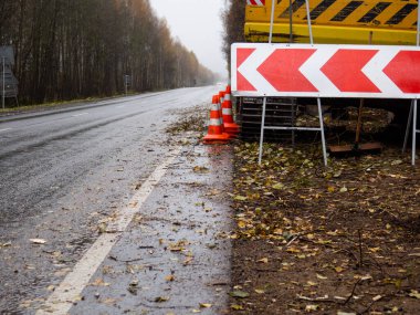 Sağdaki servis yolu tabelası. Yolun kenarında özel ekipman var. Yolda geçici trafik işaretleri var. Yolların onarımı.