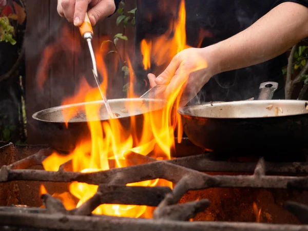 フライパンでグリルで調理する 火の上でフライパン 男がフライパンで食べ物をかき混ぜて — ストック写真