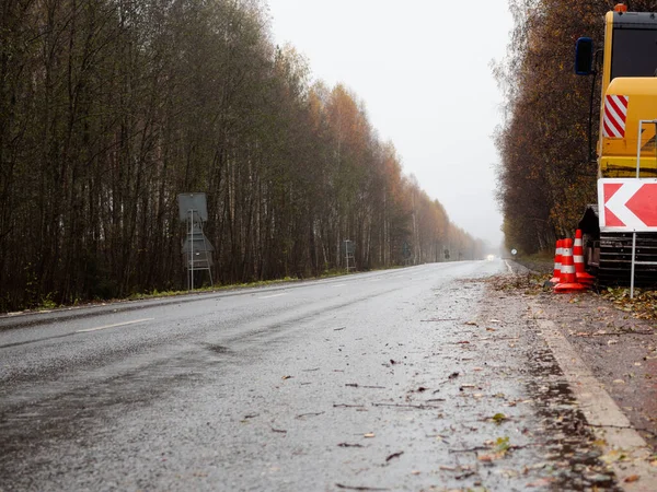 Sağdaki servis yolu tabelası. Yolun kenarında özel ekipman var. Yolda geçici trafik işaretleri var. Yolların onarımı.