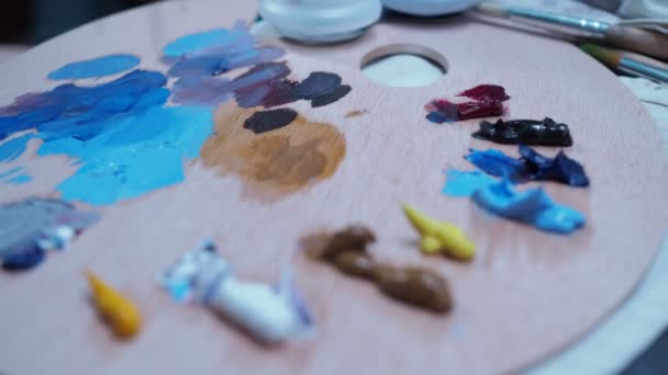 A menina mexe as tintas a óleo com um pincel da paleta. close-up — Vídeo de Stock
