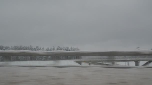 Carretera cubierta de nieve y bosques desde la ventana del coche. sendero de invierno es peligroso — Vídeo de stock