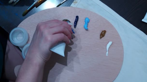 Flickornas hand klämmer ut oljefärger på en palett för att rita. ovanifrån av skjutningen — Stockvideo